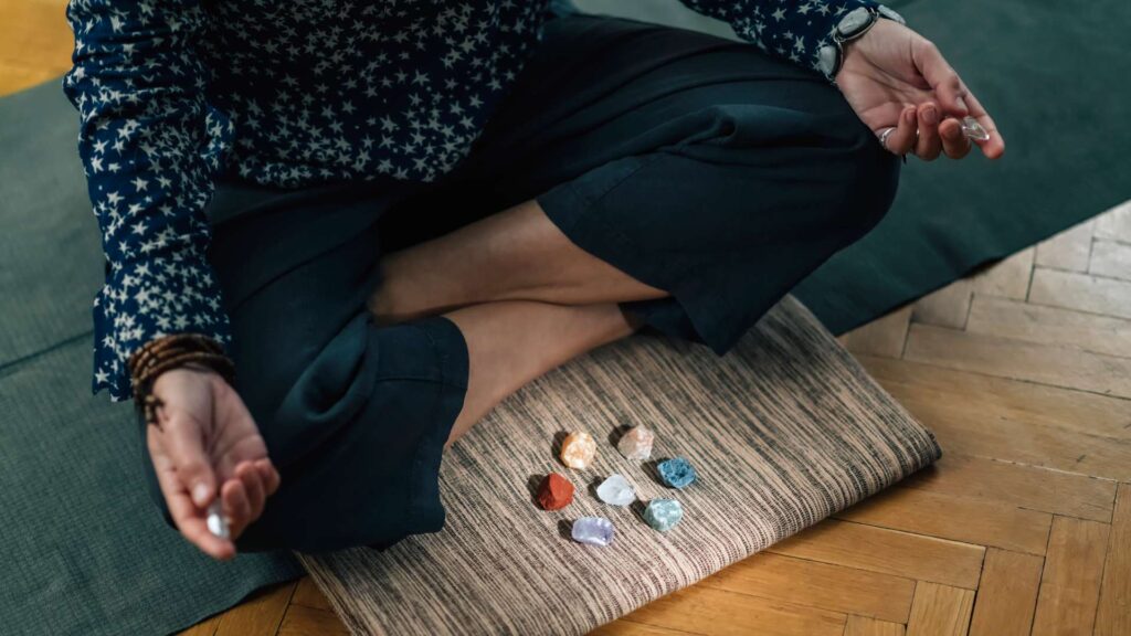 Meditating with Crystals Lotus Pose. Quartz Crystal Chakra Wand in Hands