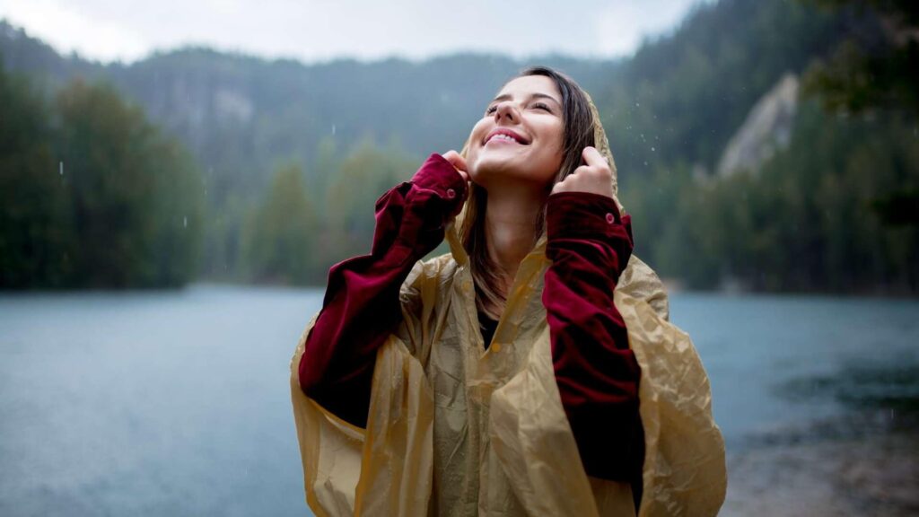 woman in raincoat near lake in rainy day
